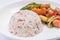 Close-up stream brown rice with blurred background of fried sausages and mixed vegetables in ketchup sauce, healthy eating