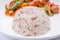Close-up stream brown rice with blurred background of fried sausages and mixed vegetables in ketchup sauce, healthy eating