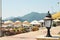 Close-up of a street lantern with bicycles, beach umbrellas and mountains on a backround