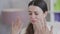 Close-up of stressed crying slim young woman with big brown eyes calming down shaking hands at face sitting in office