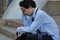 Close up stressed frustrated young Asian man sitting on stairway. he feeling disappointed or tired with something.