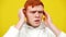 Close-up of stressed man having panic attack. Portrait of young redhead Caucasian guy having nervous breakdown at yellow