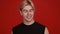 Close up studio portrait of happy blonde guy laughing at camera, red background, slow motion