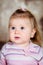 Close-up studio portrait of upset little girl with long blond hair