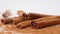 Close up studio shot of food ingredient. Brown dried cinnamon sticks laying on the white background with powder and few