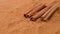 Close up studio shot of spice. Background of brown dried cinnamon powder with fractions and few sticks falling from the