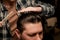 close-up on styled hair of man and hand of barber with comb