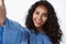 Close-up stylish and feminine curly-haired african-american woman in blue fashionable blouse, stretch hand and hold