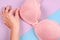 Close-up of stylish pink bra in female hand. Examines woman breasts concept. Top view