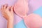 Close-up of stylish pink bra in female hand. Examines woman breasts concept. Top view.