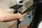 Close up of stylist hands with styling iron straightening woman hair at salon