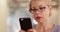 Close up of successful female wearing glasses texting on smart phone at work