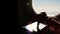 Close-up. the sun`s rays are reflected in the phone. dark silhouette of kid hands and mobile phone against airplane`s