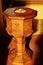 Close-up of sun shining on antique wood baptism font with trinity cross in water bowl