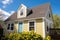 close-up of a sunny cape cod house with twin dormers