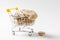 Close up of supermarket grocery push cart for shopping with yellow plastic elements on handle filled with brown stones