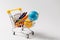 Close up of supermarket grocery push cart for shopping with yellow plastic handle with globe and colored wax pencils