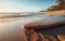 Close-up of a surfboard over the sand of a beautiful beach at sunset