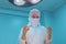 Close-up of surgeons in a sterile mask, against the background of an operating lamp, with raised hands, the surgeon`s assistant