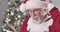 Close-up of surprised Santa Claus reading letter, looking at camera and shaking his head. Old Caucasian man with white