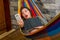 Close up of surprised young beautiful woman relaxing in a hammock and taking a selfie with her tablet while is holding a