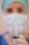 Close up syringe held by masked medic