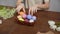 Close-up on a table with items to create a composition for Easter. Women's hands knock eggs against each other and