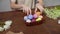 Close-up on a table with items to create a composition for Easter. Women's hands knock eggs against each other and