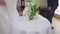 Close-up table with unrecognizable bride in wedding dress passing in slow motion leaving bridal bouquet. Blurred groom