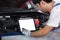 Close up Tablet empty white screen, Repairman auto mechanic using tablet white screen to check for damage inside engine.