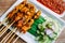 Close up A tasty BBQ pork satay recipe complete with a peanut satay sauce and cucumber sauce, onion, chili on the table with a