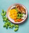 Close up of tasty chicken salad bowl with mango on light blue table background, top view. Fitness nutrition