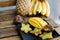 Close up tasty mango with carambola on plate near pine-apple and bananas on wooden table.