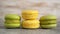 Close up of tasty stacked yellow and green macaron cakes on grey table. Pistachio and lemon french macaroons