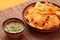 Close up of tasty tortilla corn chips and basil pesto sauce in a bowl