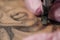 Close-up of a tattoo needle. The process of the tattoo master. Pink women`s protective gloves.