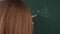 A close-up of a teacher talking to a student near the blackboard.