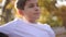 Close up of Teenage boy in white sweater sitting on the bench. Handsome school boy with backpack in autumn park