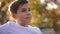 Close up of Teenage boy in white sweater sitting on the bench. Handsome school boy with backpack in autumn park