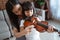 Close up of teenage girls help a child hold the violin bow properly while playing the violin indoors