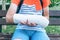 Close up Teenage`s hand with broken hand in a cast on the bench in the park. Boy in white t shirt holds his injured hand
