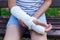 Close up Teenage`s hand with broken hand in a cast on the bench in the park. Boy in white t shirt holds his injured hand