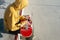 Close-up of a teenager dressed in a sweatshirt jeans and sneakers sitting in a skate park holding a phone and a