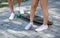 A close-up of teenages` legs in white sneakers resting after extreme funny ride on a wooden longboard skateboard. Copy space.