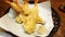 Close up Tempura with Garlic smoothie on white oil paper on black basket at Japanese restaurant. Deep fried shrimp or prawn