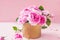Close up tender pink tea roses bouquet in vintage golden pot on the pink background. Postcard mock up. Summer, spring flowers. Sel