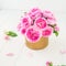 Close up tender pink tea roses bouquet in vintage golden pot on the white wooden table. Floral background. Postcard mock up. Summe