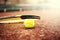 Close-up of tennis ball and racket on clay court