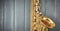 Close-up of tenor saxophone, bell and keys, lacquered in gold on gray wood