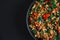 Close up of Texas Caviar: delicious one pan fried vegetable mix with tofu, low fat, vegetarian, on a black background, top view.